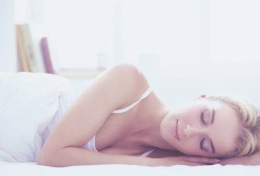 Güzel bir kadın yatağında uzanıyor.