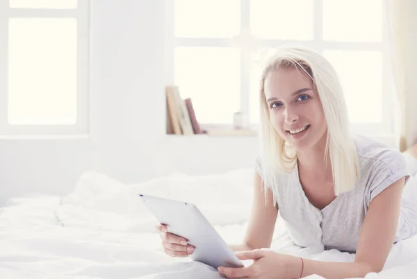 Meisje met digitale tablet met blanco scherm en glimlach op de camera in de slaapkamer — Stockfoto