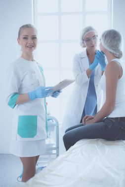 Güzel kadın elinde şırıngayla doktorun yanında duruyor.