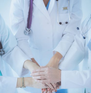 Doktorlar ve hemşireler tıbbi bir ekipte el ele tutuşuyorlar.