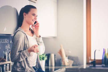 modern mutfakta otururken cep telefonu kullanan kadın.