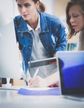 Masanın yanında duran iki genç kadın enstrüman, plan ve dizüstü bilgisayarla.