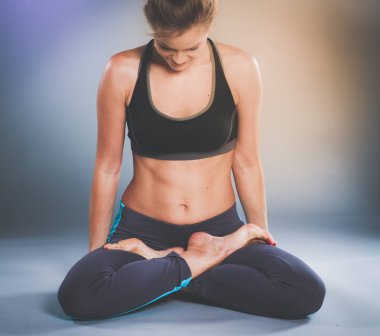 Lotus pozisyonu yerde oturan bir genç bayan. Yoga
