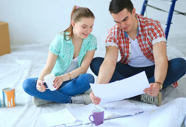 Pareja joven sentada en el suelo y calculando sobre sus ahorros. Pareja joven — Foto de Stock