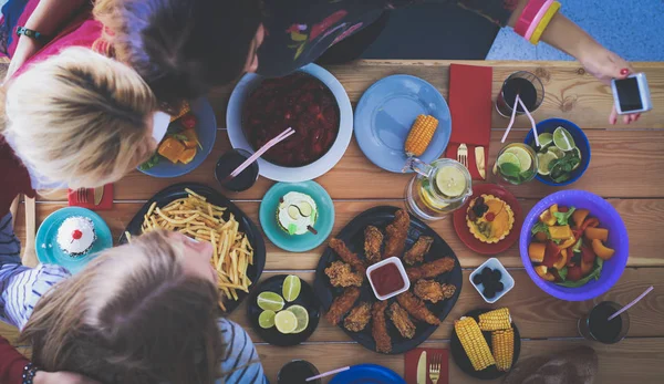 Widok z góry na grupę ludzi jedzących razem kolację siedząc przy drewnianym stole. Jedzenie na stole. Ludzie jedzą fast food. — Zdjęcie stockowe