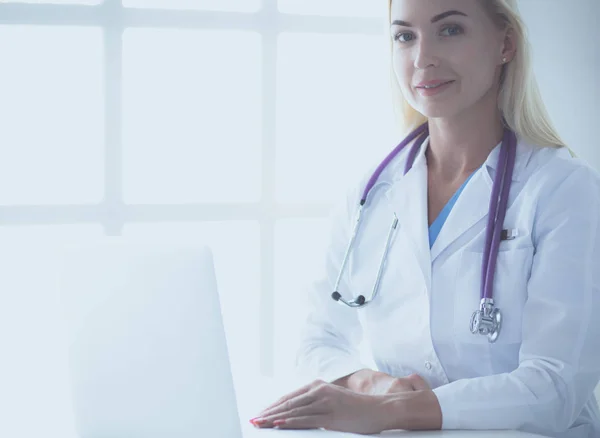 Doctora sentada en el escritorio y trabajando en un portátil en el hospital — Foto de Stock