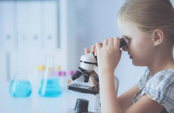 Skolflicka tittar genom mikroskopet i science klass. — Stockfoto