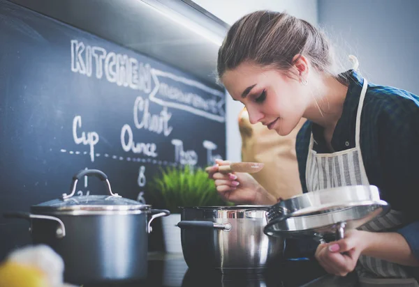 Junge Frau steht am Herd in der Küche . — Stockfoto