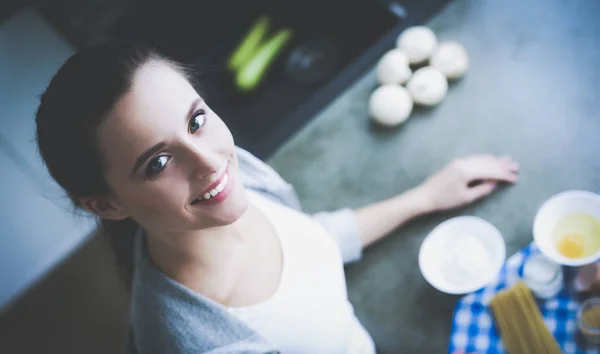 Belle femme cuisine gâteau dans la cuisine debout près du bureau. — Photo