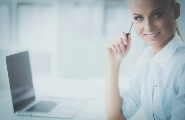 Aantrekkelijke zakenvrouw zit op een bureau met laptop in het kantoor — Stockfoto