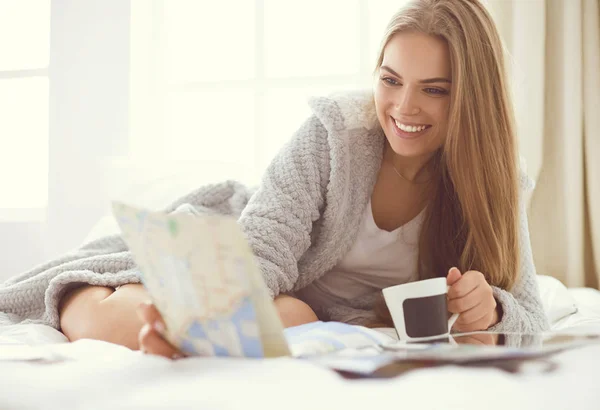 Entspannte junge Frau sitzt mit einer Tasse Kaffee und digitalem Tablet im Bett — Stockfoto
