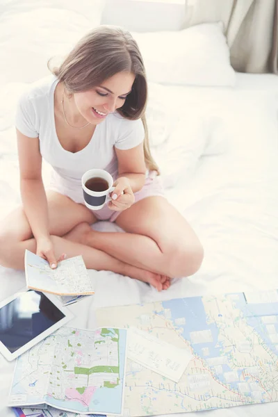 Entspannte junge Frau sitzt mit einer Tasse Kaffee und digitalem Tablet im Bett — Stockfoto