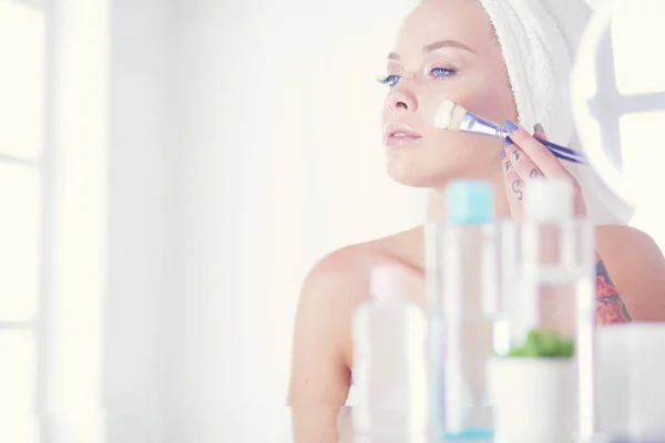 Una foto de una mujer joven aplicando polvo facial en el baño — Foto de Stock