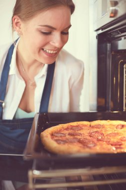 Mutlu genç bayan evde pizza pişiriyor.