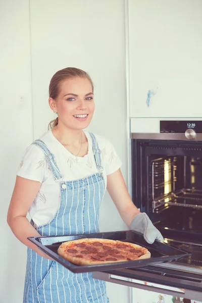 Glad ung kvinde madlavning pizza derhjemme - Stock-foto