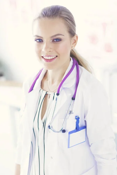 Smiling female doctor with a medical stethoscope in uniform standing Stock Photo