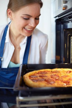 Mutlu genç bayan evde pizza pişiriyor.