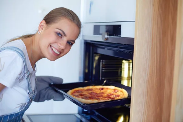 Gelukkig jong vrouw koken pizza thuis — Stockfoto