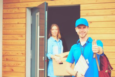 Mavi üniformalı gülümseyen kurye servis konseptine paket kutusu teslim eden teslimatçı. Mavi üniformalı gülümseyen teslimatçı.