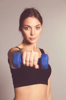 Atletik kadın dambıllarla kaslarını şişiriyor..