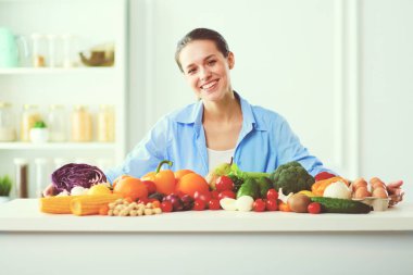 Ahşap iç kısımda meyve ve sebze dolu masada oturan genç ve tatlı bir kadın..