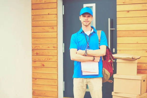 Smiling delivery man in blue uniform delivering parcel box to recipient - courier service concept. Smiling delivery man in blue uniform — Stock Photo, Image