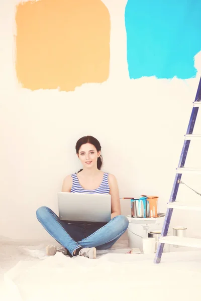 Junge Frau beim Bemalen der neuen Wohnung, sitzend mit Laptop. junge Frau mit Laptop — Stockfoto