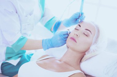 Kaşlar için kalıcı makyaj. Güzellik salonunda kalın kaşlı güzel bir kadın..