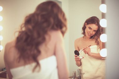 Telefon ile banyo üzerinde duran genç kadın.