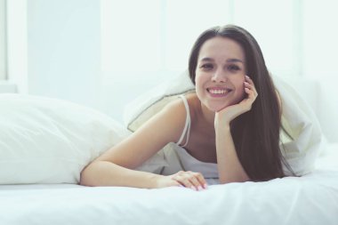 Güzel bir kadın yatağında uzanıyor..