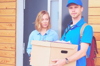 Mavi üniformalı gülümseyen kurye servis konseptine paket kutusu teslim eden teslimatçı. Mavi üniformalı gülümseyen teslimatçı.