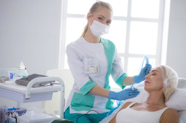 Kaşlar için kalıcı makyaj. Güzellik salonunda kalın kaşlı güzel bir kadın..