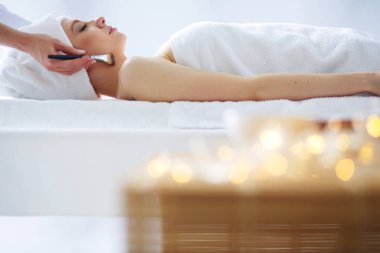 Masaj masasında uzanmış gözleri kapalı rahatlayan genç bir kadın. - Kadın. Spa salonu