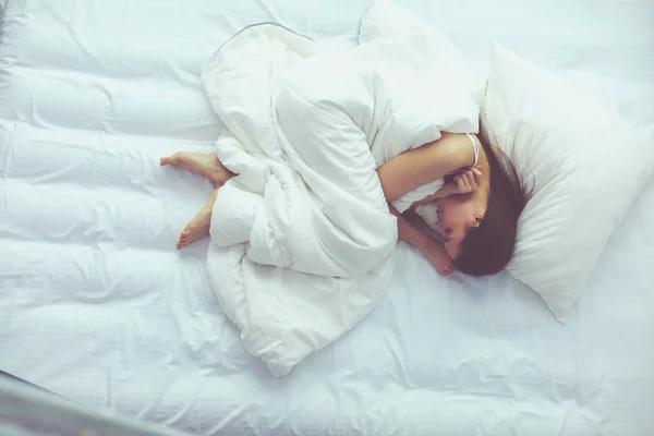 Unga kvinnliga känner smärta i sängen. — Stockfoto