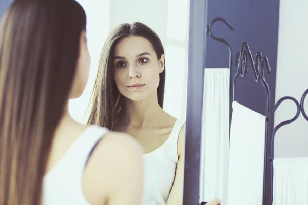 Jovem mulher olhando-se reflexão no espelho em casa . — Fotografia de Stock