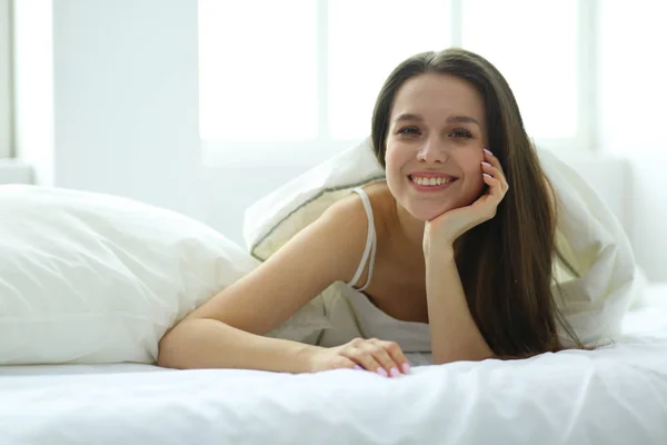 Pretty woman lying down on her bed at home.