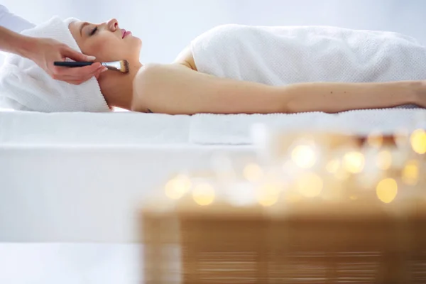 Jovem deitada em uma mesa de massagem, relaxando com os olhos fechados. Mulher. Salão de Spa — Fotografia de Stock