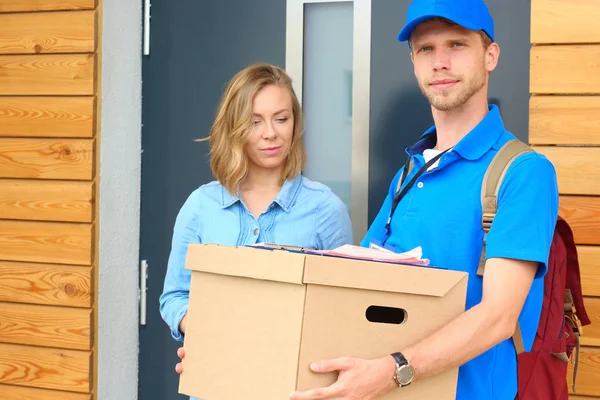Mavi üniformalı gülümseyen kurye servis konseptine paket kutusu teslim eden teslimatçı. Mavi üniformalı gülümseyen teslimatçı.
