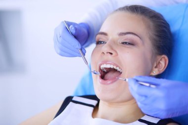 Dişçi muayenehanesinde diş muayenesi yapan ağzı açık genç bir kadın hasta..