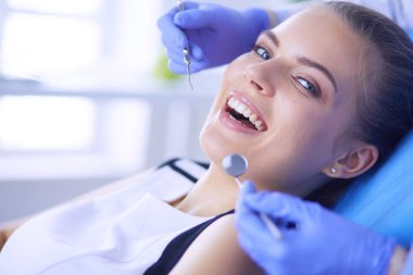 Dişçi muayenehanesinde diş muayenesi yapan ağzı açık genç bir kadın hasta..