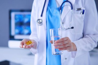 Doktorlar ellerinde haplar ve klinikte bir bardak su tutarken..