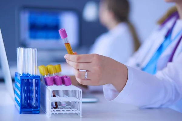 Asistente de laboratorio poniendo tubos de ensayo en el soporte, Vista de primer plano se centró en los tubos con pruebas . —  Fotos de Stock