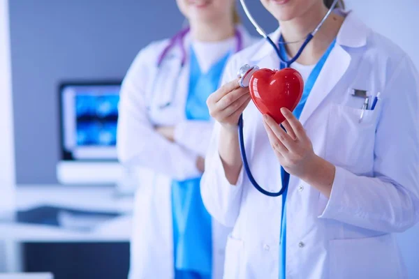 Pouls recadré de deux jeunes médecins femelle avec stéthoscope tenant le cœur. — Photo