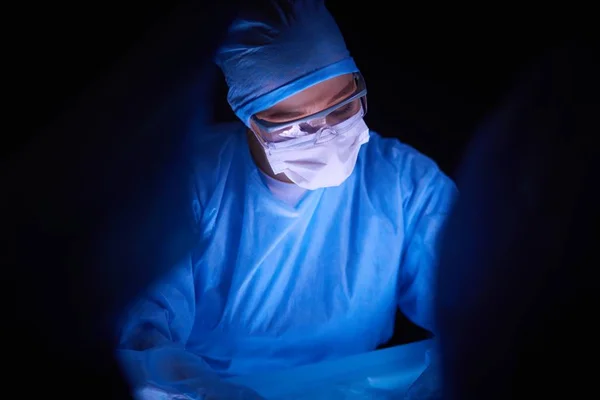 Лікар виконує операцію на темному фоні . — стокове фото