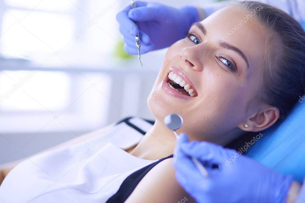 Young Female patient with open mouth examining dental inspection at dentist office.