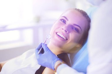 Güzel gülüşü olan genç bir bayan hasta dişçi muayenesi için dişçiye gidiyor..