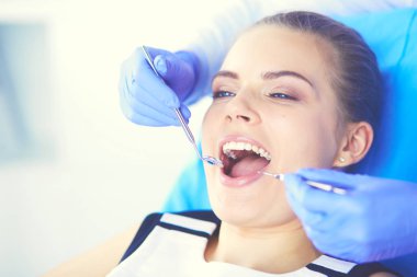 Dişçi muayenehanesinde diş muayenesi yapan ağzı açık genç bir kadın hasta..