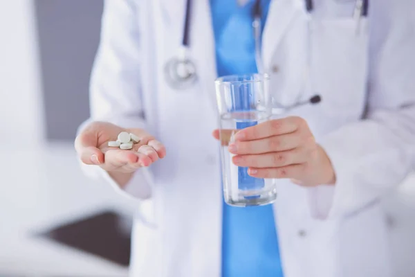 Primo piano di medici mani in possesso di pillole e bicchiere d'acqua. — Foto Stock