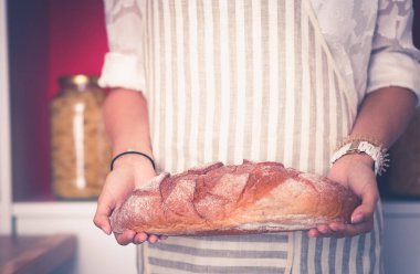 Genç bir kadın mutfağında ekmeği holding ayakta. Genç bir kadın