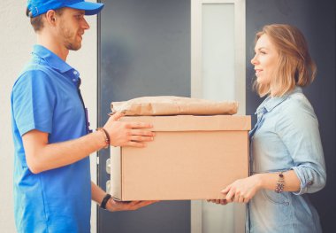 Mavi üniformalı gülümseyen kurye servis konseptine paket kutusu teslim eden teslimatçı. Mavi üniformalı gülümseyen teslimatçı.